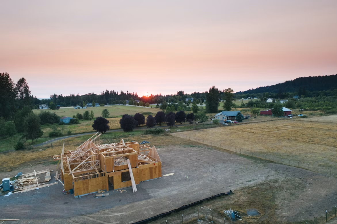Barn construction site with timber framing and organized debris-clearing area