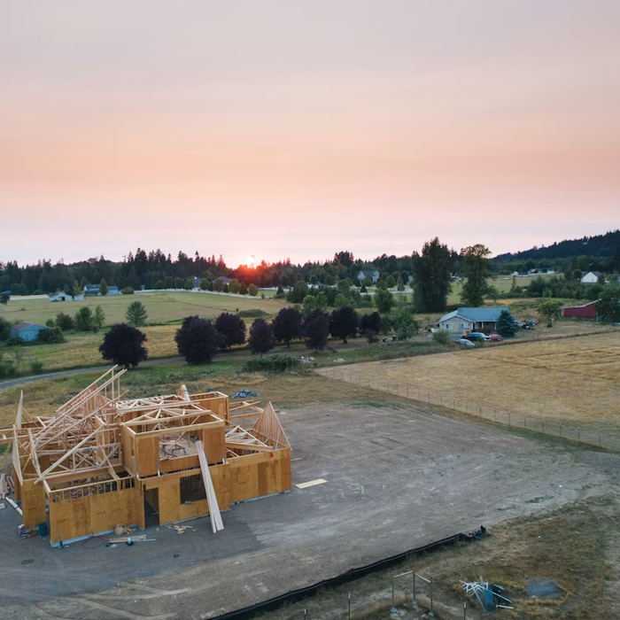 Barn construction site with timber framing and organized debris-clearing area