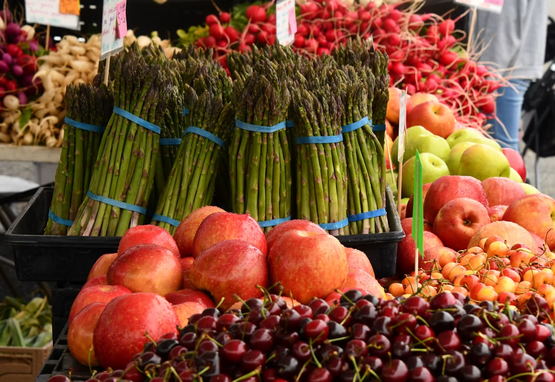 Seasonal asparagus, apples, radishes, and cherries at a farmers market