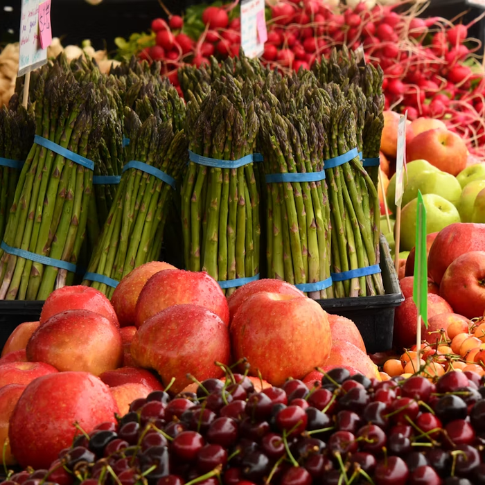 Seasonal asparagus, apples, radishes, and cherries at a farmers market