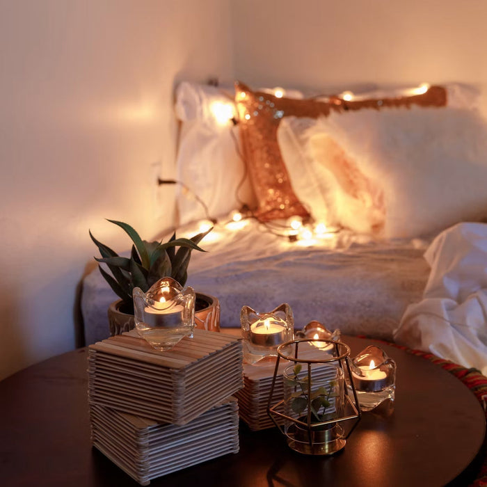 Cozy bedroom with pillows, blankets, candles, and warm string lights