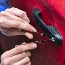 Locksmith using non-destructive tools on a red vehicle door