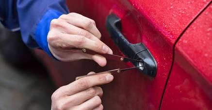 Locksmith using non-destructive tools on a red vehicle door