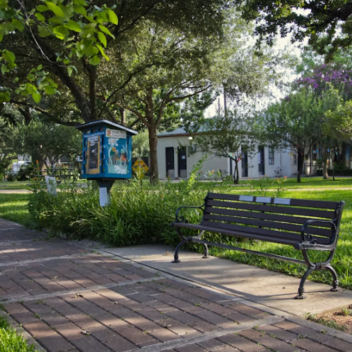Tree-lined neighborhood park with a bench and walking path