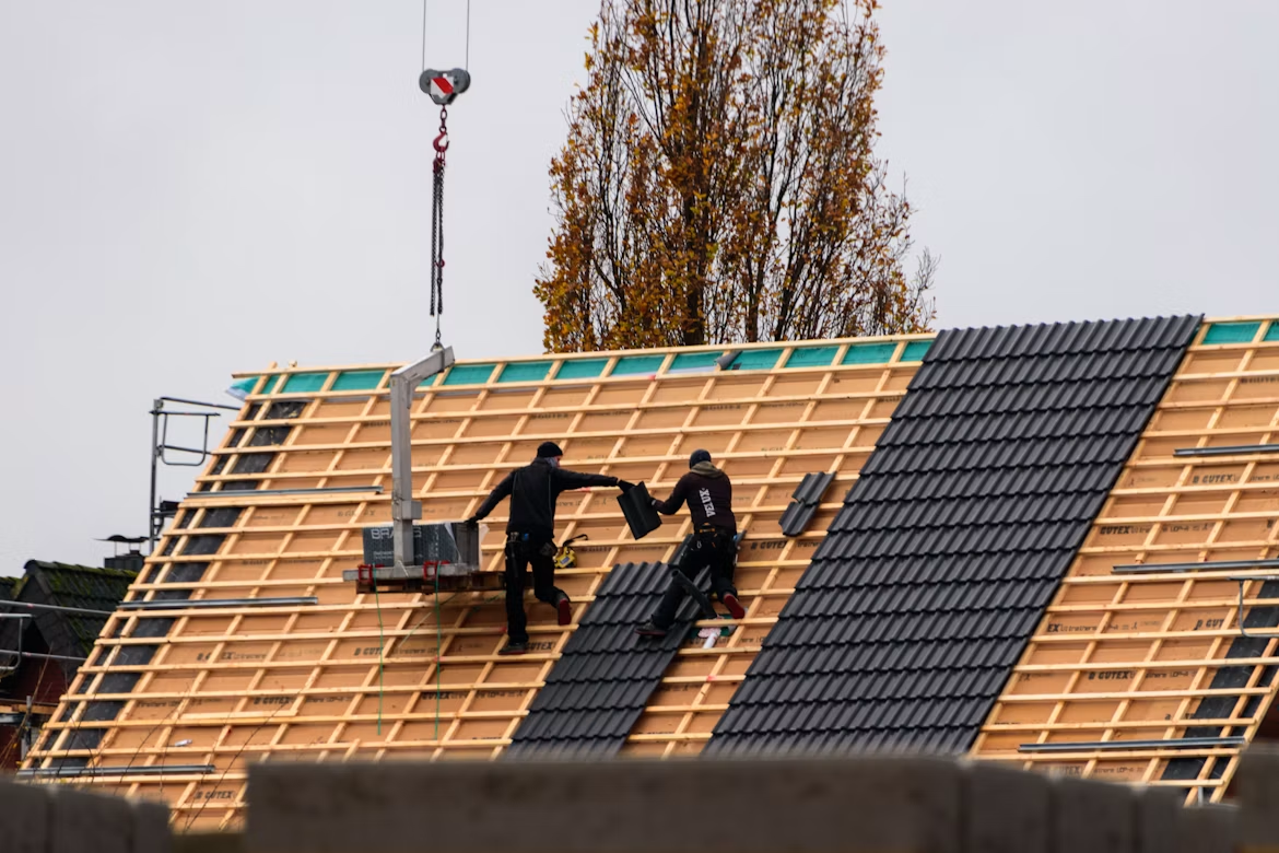 Roofers installing tiles on a residential roof