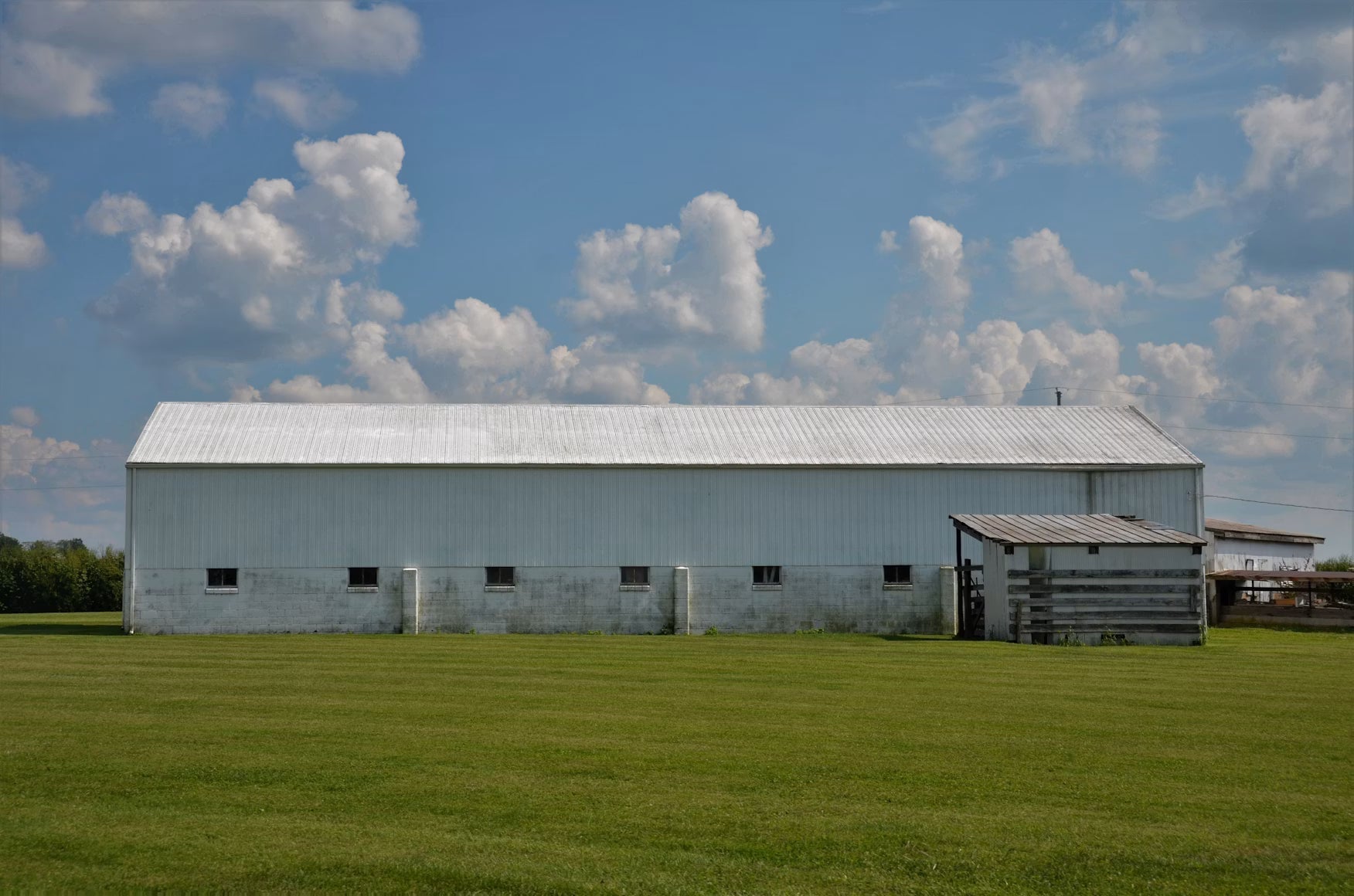 Large metal farm building beside a fenced pasture