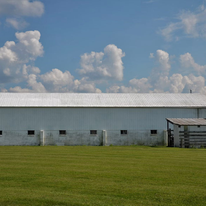 Large metal farm building beside a fenced pasture