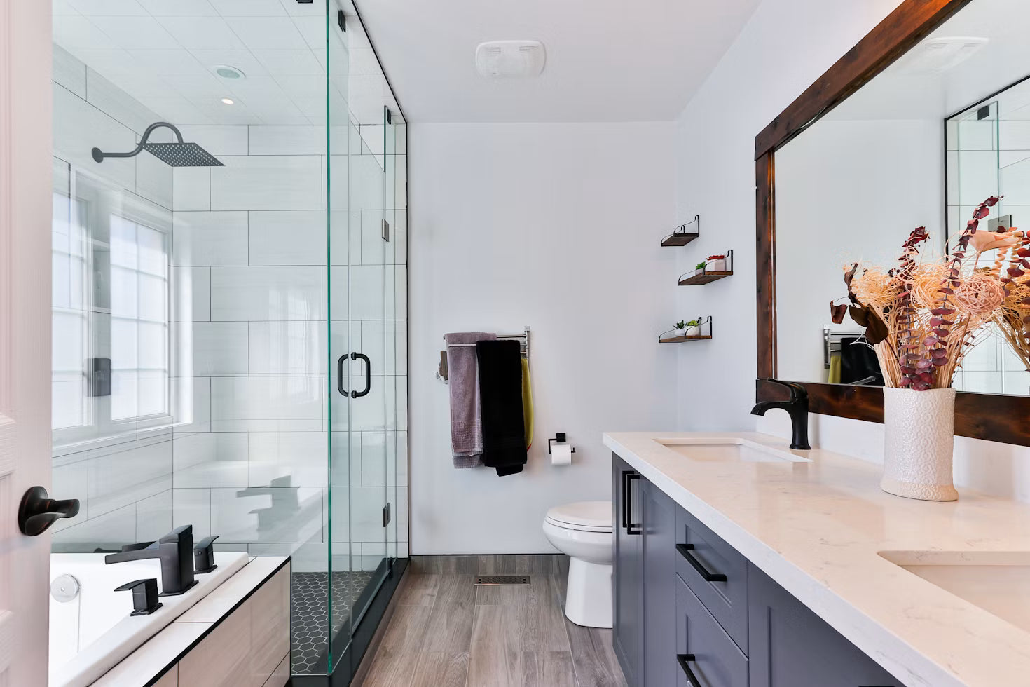 Modern bathroom with a glass shower, white vanity, and freestanding tub