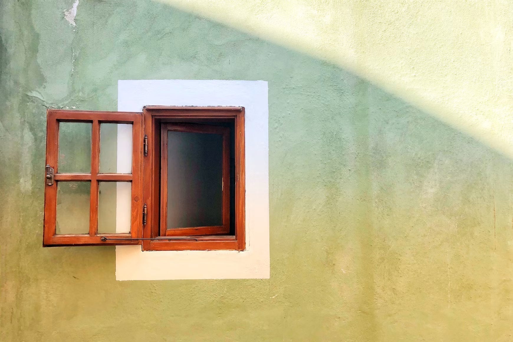 Open wood-framed window set in a stucco wall