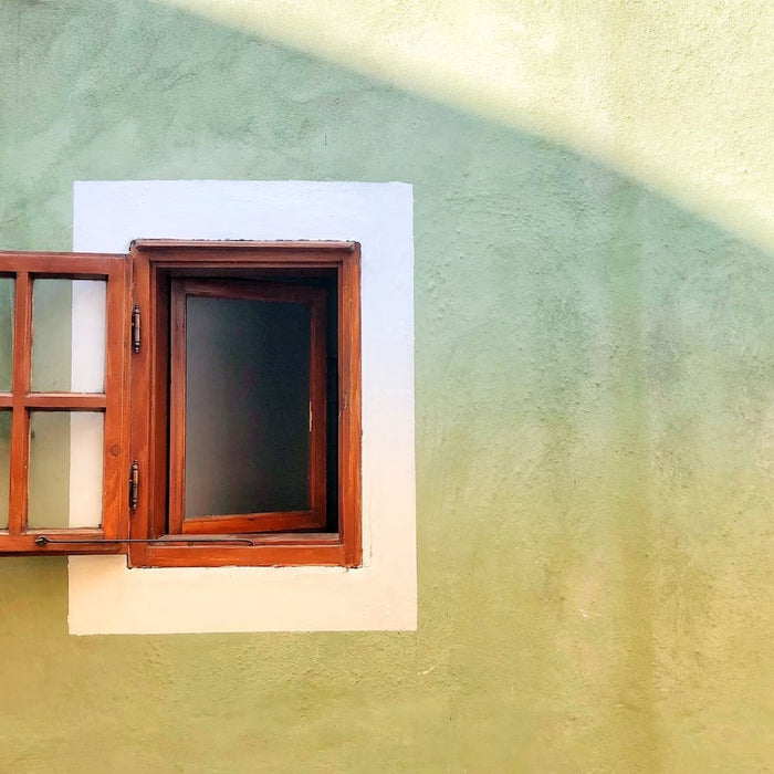 Open wood-framed window set in a stucco wall