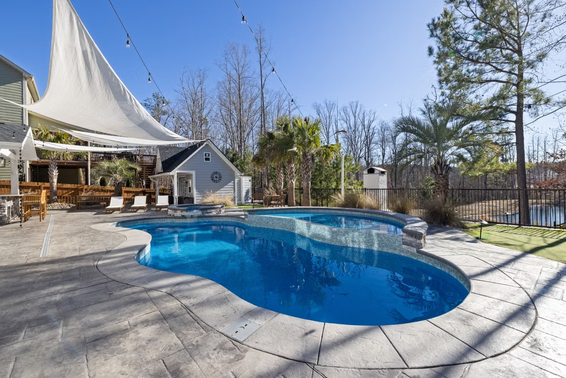 Renovated backyard swimming pool with palm trees and deck