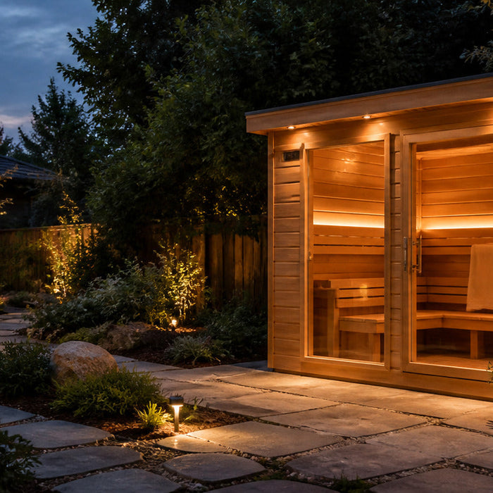 Cedar outdoor sauna beside a stone garden path at dusk