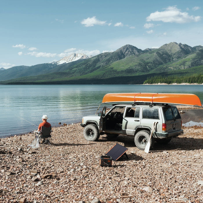 Portable power station and solar panel beside a lakeside campsite