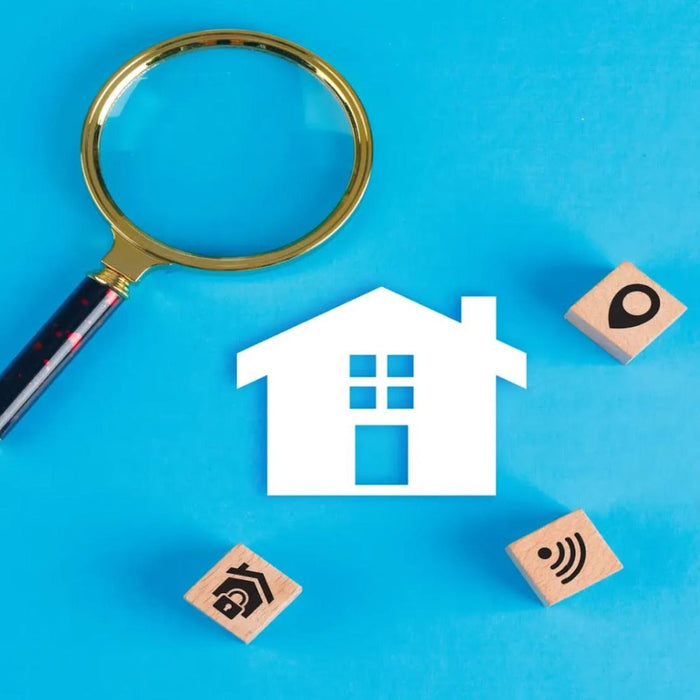 Magnifying glass beside a model house and rental property icons