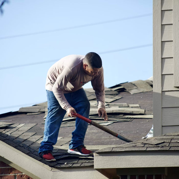 Worker removing old shingles from a residential roof