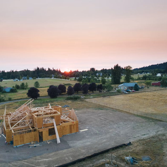 Aerial view of a timber-framed building under construction on cleared land