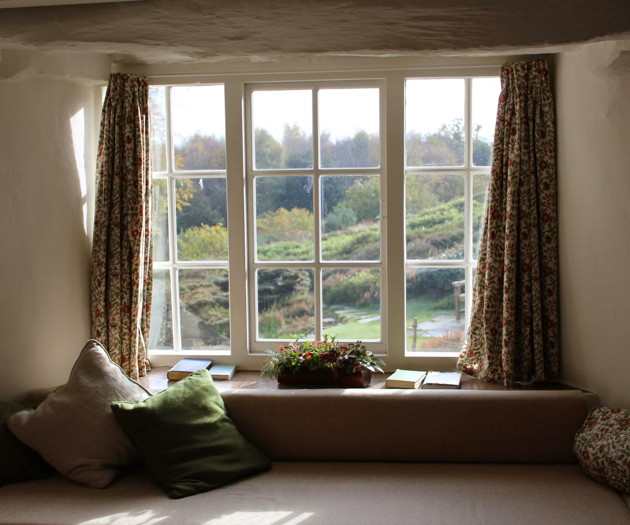 Sunlight entering through a sash window with patterned curtains