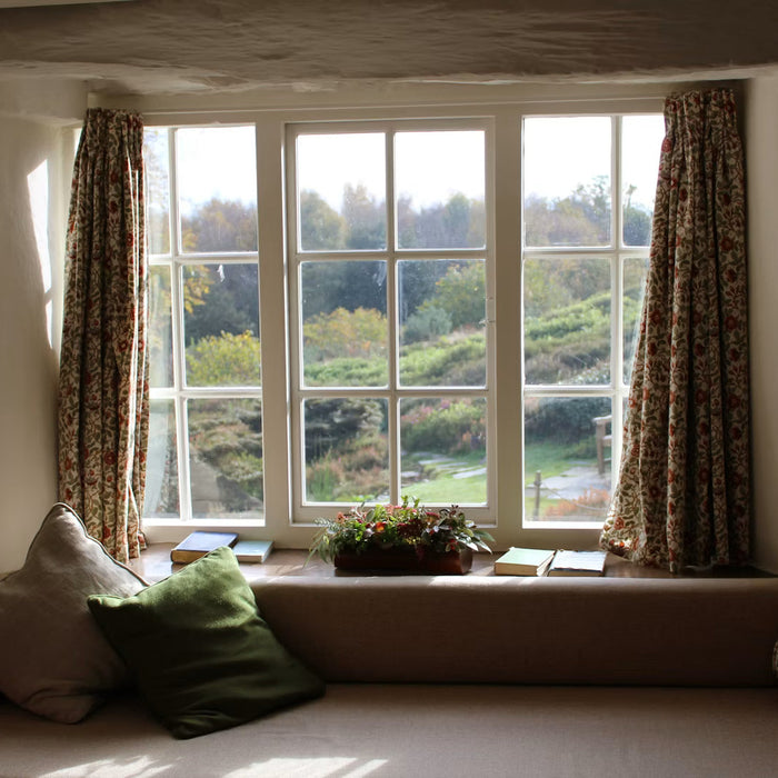 Sunlight entering through a sash window with patterned curtains