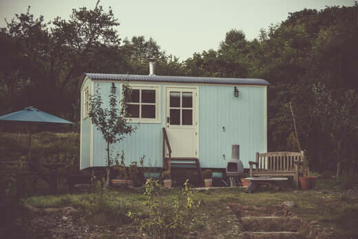 Small backyard storage shed beside trees and outdoor furniture