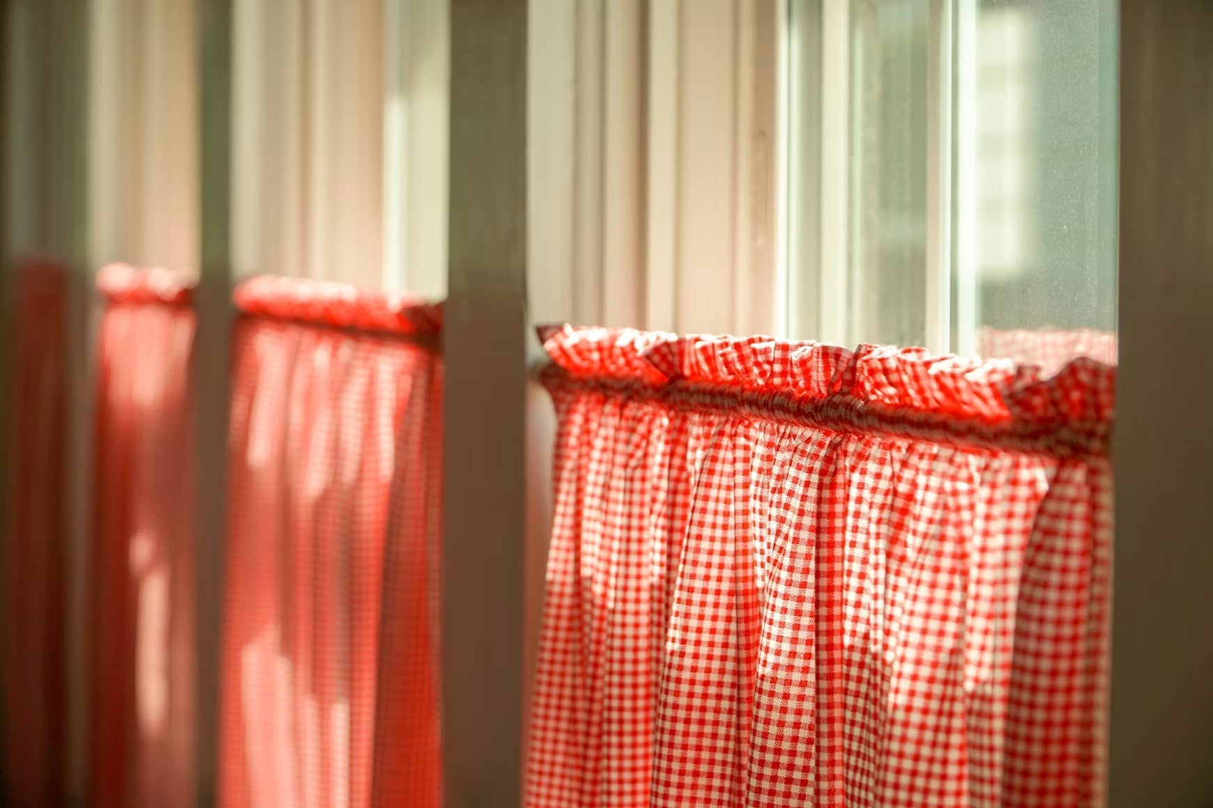 Sunlight entering through a sash window with red checked curtains