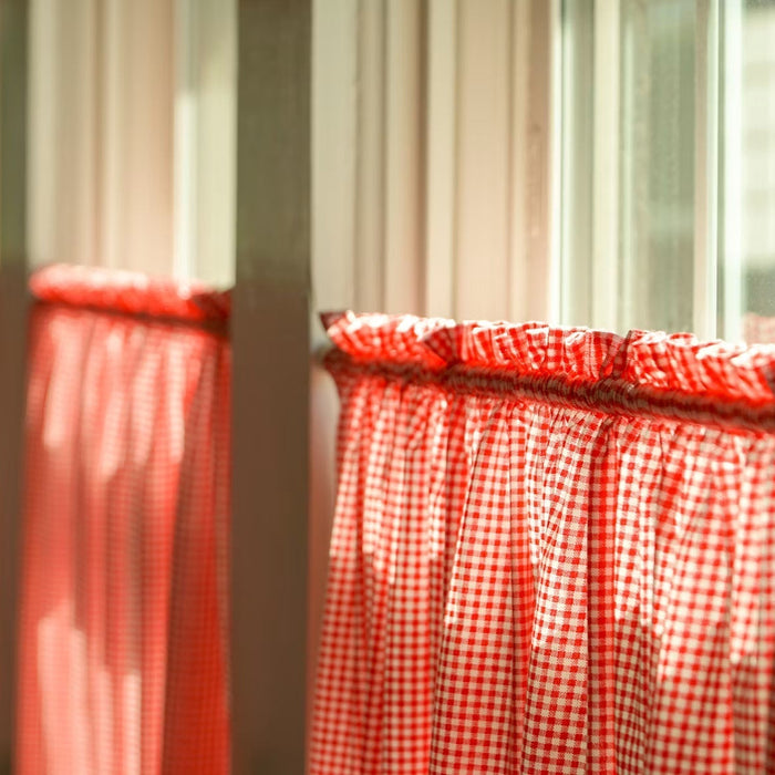 Sunlight entering through a sash window with red checked curtains