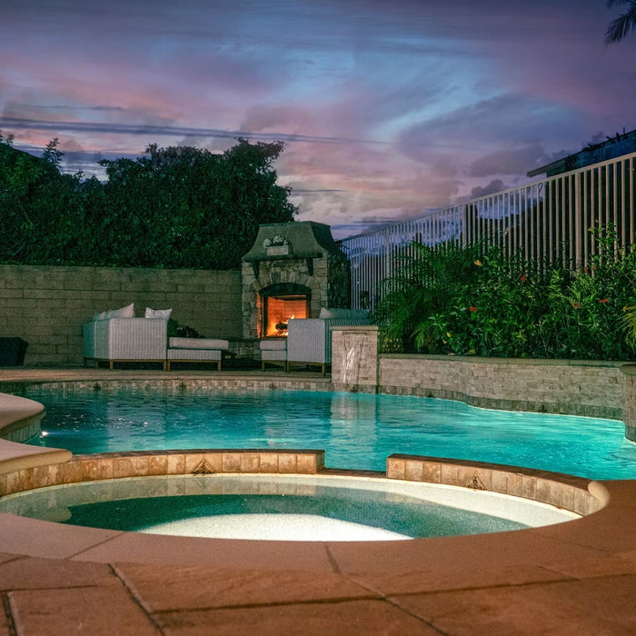 Backyard pool and spa beside an outdoor fireplace at sunset