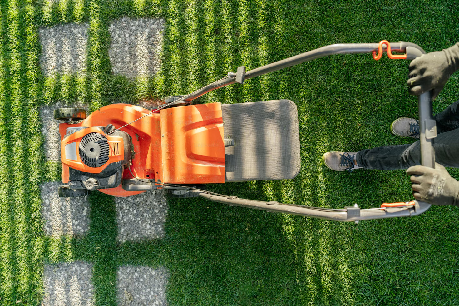 Orange zero-turn mower cutting a striped lawn
