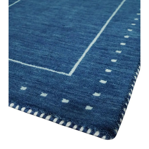 Close corner view of the blue field, pale inner line, border motifs, and contrasting edge binding
