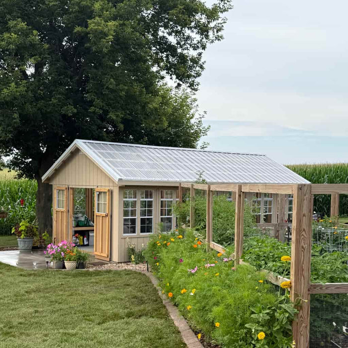 Ez fit greenhouse with a garden path leading to it, surrounded by greenery and flowers.