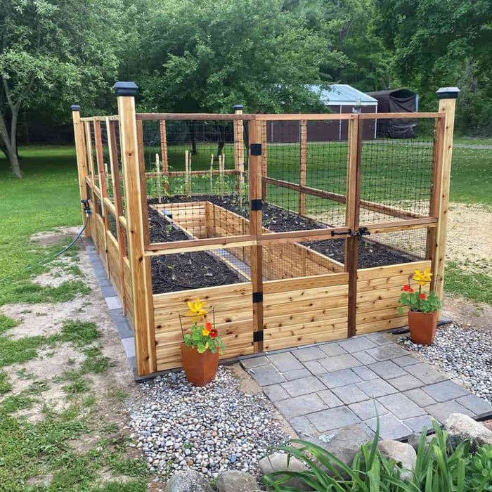 Outdoor Living Today 8x16 Deer Proof cedar raised garden bed with plants and flowers in a backyard setting.