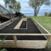 Outdoor Living Today 8x16 cedar raised garden bed with soil in a grassy area near a body of water.