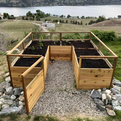 Cedar raised garden bed with plants on a rocky outcrop overlooking a lake.