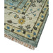 Close view of an aqua and ivory rug corner with fringe