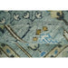 Folded edge of the aqua and ivory wool rug showing the pile and tree design