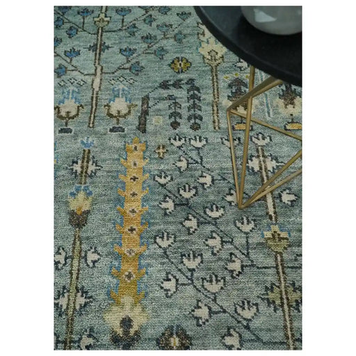Styled close view of the aqua and ivory tree motif rug beneath a table leg