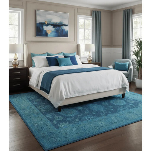 Blue traditional Oushak wool rug styled under a bed in a bedroom