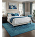 Blue traditional Oushak wool rug styled under a bed in a bedroom