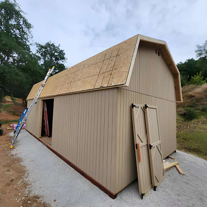 Brown gambrel large barn with open door in a rural setting