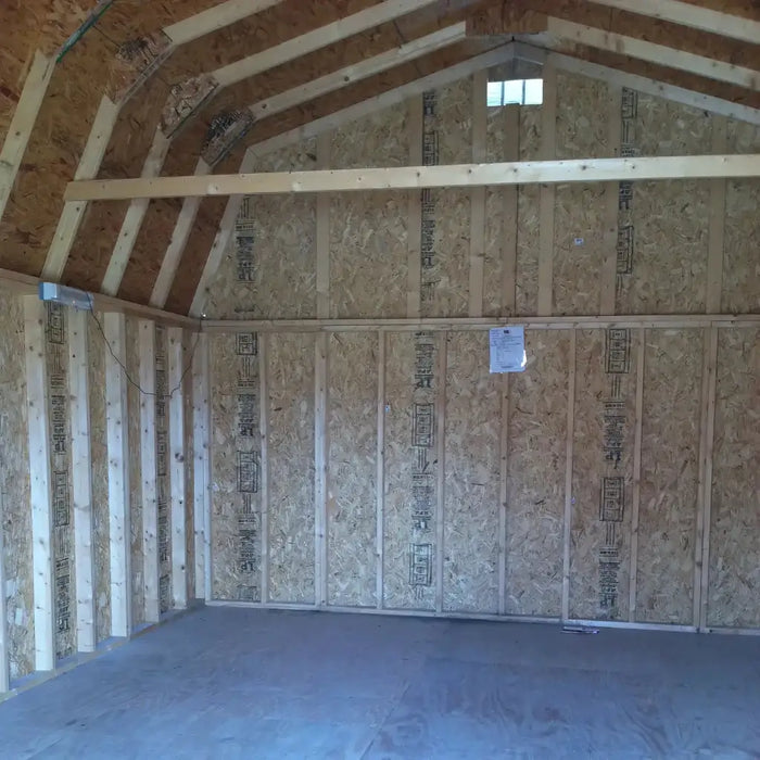 Unfinished interior of little cottage co gambrel large barn with wooden framing and drywall.
