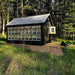Little cottage co colonial gable greenhouse in black with glass windows in a forest setting