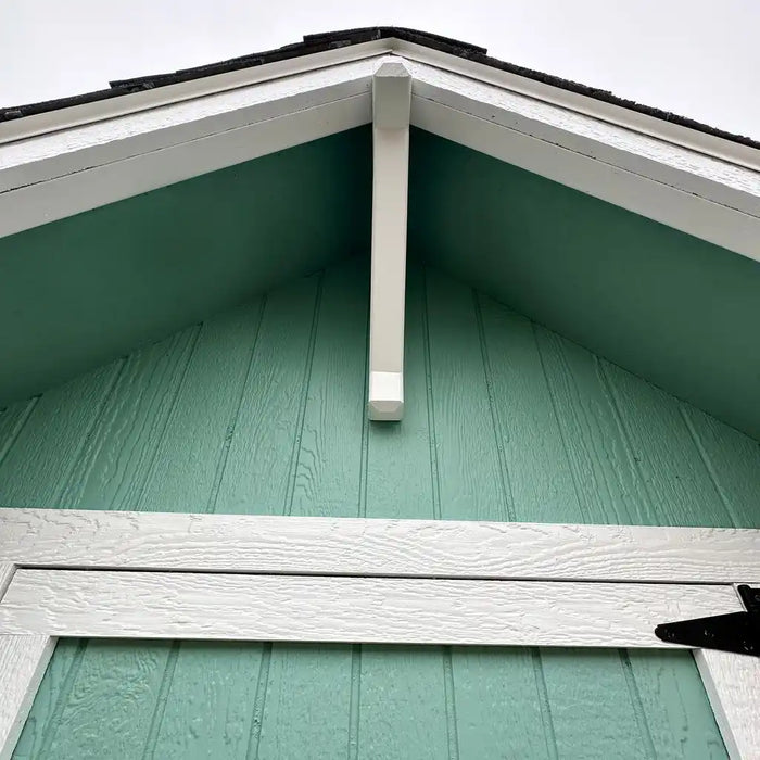 Little Cottage Co Craftsman Playhouse close-up of a gable batten with green shingles and white gutters.