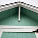 Little Cottage Co Craftsman Playhouse close-up of a gable batten with green shingles and white gutters.