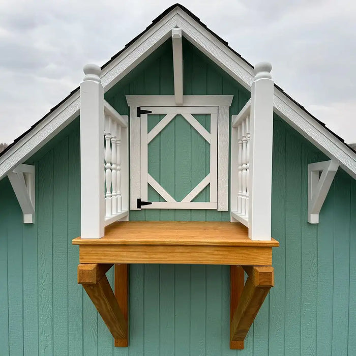 Little Cottage Co Craftsman Playhouse with a wooden platform and white railing against a cloudy sky.