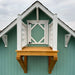 Little Cottage Co Craftsman Playhouse with a wooden platform and white railing against a cloudy sky.