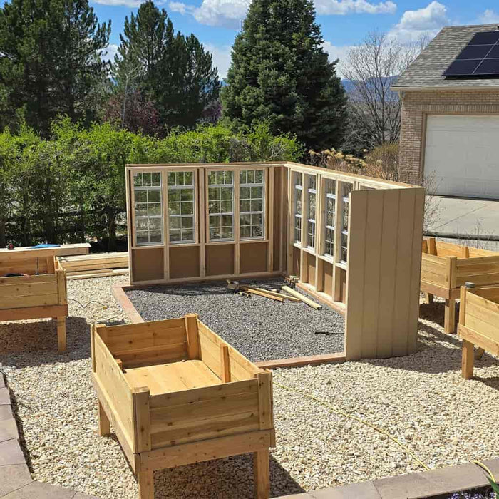 Ez fit greenhouse shed kit under construction in a backyard with gravel foundation.