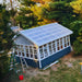 EZ-Fit Greenhouse Kit with solar panels on the roof surrounded by trees