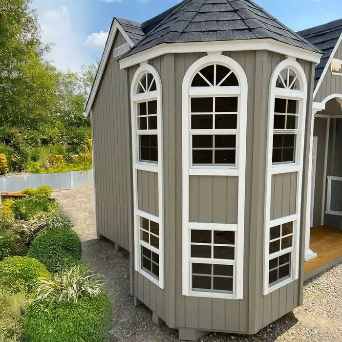 Little cottage co grand portico mansion playhouse kit with arched windows in a garden setting