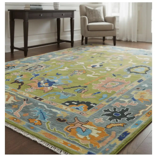 Green, Gray and Peach Oushak rug shown in a furnished room with a desk and armchair.
