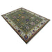 Angled full view of the green and ivory Oushak area rug on a plain background