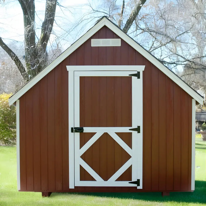 Red little cottage co firehouse playhouse kit with white trim and door in a garden setting